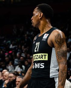 a basketball player standing in front of an audience with tattoos on his arm and shoulder