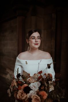 a woman wearing glasses holding a bouquet of flowers