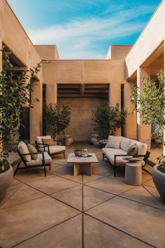 Modern outdoor patio with minimalistic furniture, surrounded by potted plants under a blue sky. Concrete Patio Makeover Ideas, Concrete Patio Decorating Ideas, Patio Makeover Ideas, Concrete Patio Ideas, Patio Ideas On A Budget, Concrete Patio Makeover, Concrete Patio Designs, Tuscan Design, Budget Patio