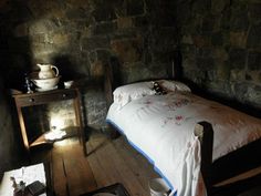 a bed sitting in a bedroom next to a table with a lamp on top of it