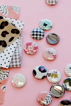 some buttons that are on top of a pink surface with the words, diy make pin back buttons