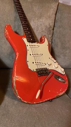 an old red guitar sitting on top of a couch