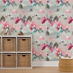 a room with a dresser and wallpaper that has mountains on it