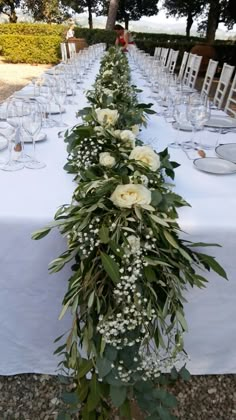 a long table with white flowers and greenery