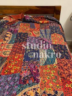 the bed is made up with colorful quilts