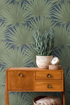 a wooden table with a potted plant on top of it next to a wallpaper