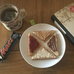 a white plate topped with sandwiches next to a cup of coffee and a stack of books