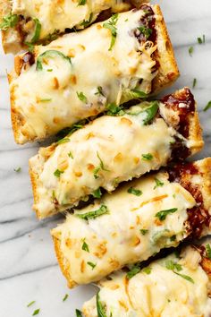 four pieces of bread with cheese and sauce on them sitting on a marble counter top