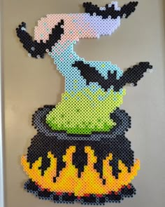 a piece of art made out of perler beads with an image of a bird sitting on top of a pot