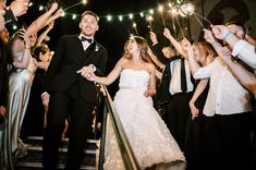 a bride and groom walk down the stairs with sparklers in their hands as they exit