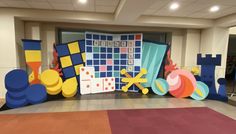 an indoor area with large paper cutouts and colorful rugs on the floor in front of it