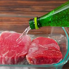 raw meat being poured into a glass bowl with water on the side and a green bottle next to it