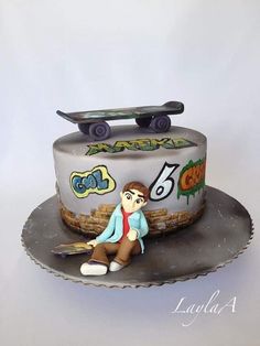 a birthday cake with a skateboard on top and a man sitting on the ground