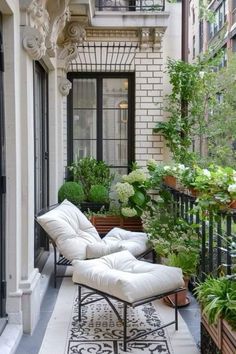 an outdoor patio with white furniture and potted plants on the side of the building