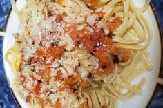 a plate of pasta with meat and tomato sauce on the top is sitting on a blue tablecloth