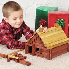 a young boy playing with wooden toys in front of christmas presents on the floor,