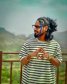 a man with long hair and glasses standing in front of a painting