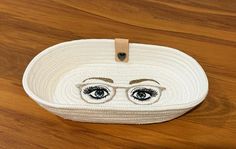 a woven basket with eyes on it sitting on a wooden table