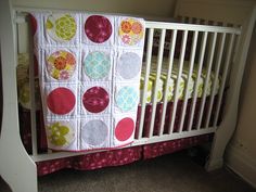 a white crib with a pink and yellow quilt on it