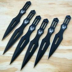 six knives with black handles on a wooden table