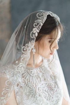 a woman wearing a wedding veil with an intricate lace design on the top and bottom