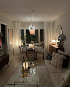 a living room filled with furniture next to a window covered in white curtains and lights