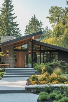 a modern house in the woods with steps leading up to it's front door