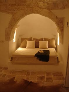 a bed sitting in the middle of a room under a stone arch next to a doorway