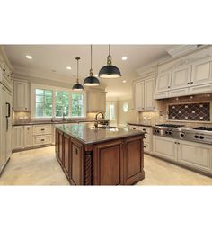 a large kitchen with an island in the middle and two pendant lights hanging from the ceiling