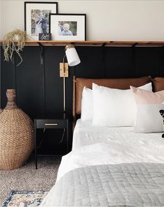 a bed with white sheets and pillows next to a black headboard on a wall