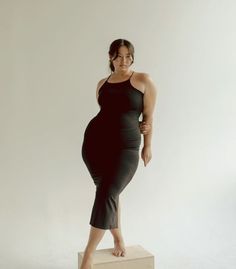 a woman standing on top of a box posing for a photo in front of a white background