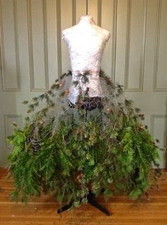 a mannequin made out of fake plants and branches on a wooden floor in front of a door