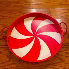 a red and white tray with a candy cane design on the bottom sitting on a wooden floor