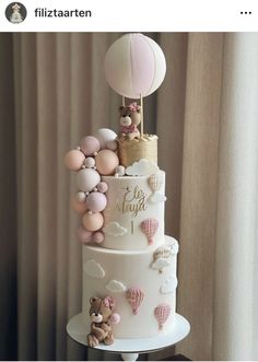 a three tiered cake with balloons and teddy bears on the top is decorated in pastel colors