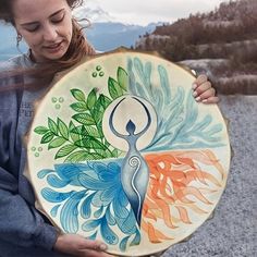 a woman holding a painted plate in her hands