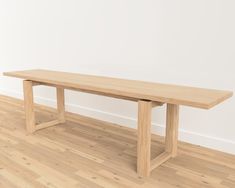 a wooden table sitting on top of a hard wood floor next to a white wall