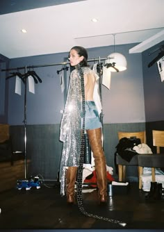 a woman standing in front of a mirror with her back turned to the camera and wearing boots