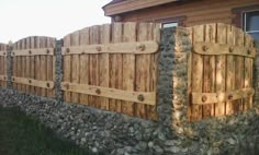 a stone and wood fence next to a house