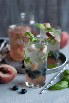 two glasses filled with ice and fruit on top of a table