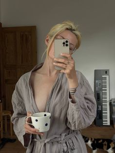 a woman taking a selfie with her cell phone and holding a cup in front of her