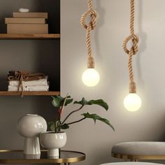 two lights are hanging on the wall next to a table with a potted plant