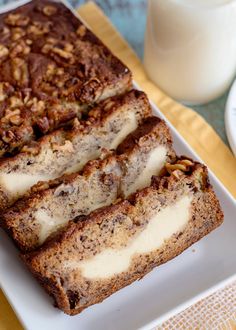 two slices of banana nut bread on a plate next to a glass of milk and fork