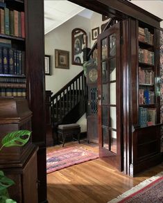 an open door leading to a room with bookshelves and stairs in the background