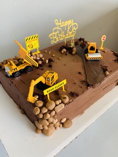 a birthday cake decorated with construction vehicles and rocks