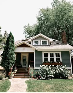 a gray house with white flowers and trees