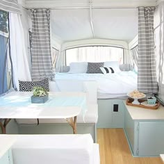 the inside of a camper with white furniture and curtains