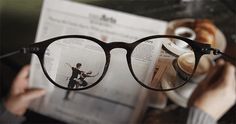 a woman reading a book while holding up her glasses with the words good morning on it