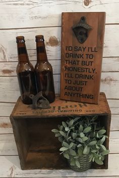 three beer bottles sitting on top of a wooden crate next to a sign that says i'd say i'll drink to that but honesty, i'll drink just about anything