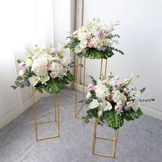 three gold plant stands with flowers in them