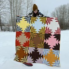 a person standing in the snow holding a quilt